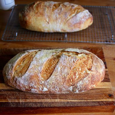 two loaves of bread sitting on top of a wooden cutting board