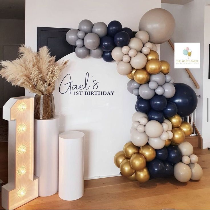 the balloon arch is decorated with gold, silver and black balloons for a birthday party