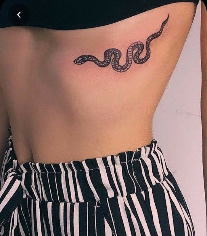 a woman's stomach with a snake tattoo on her lower side ribcage