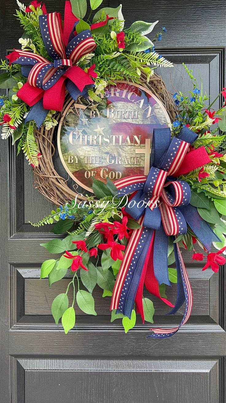 a wreath with red, white and blue ribbons hanging on the front door for christmas