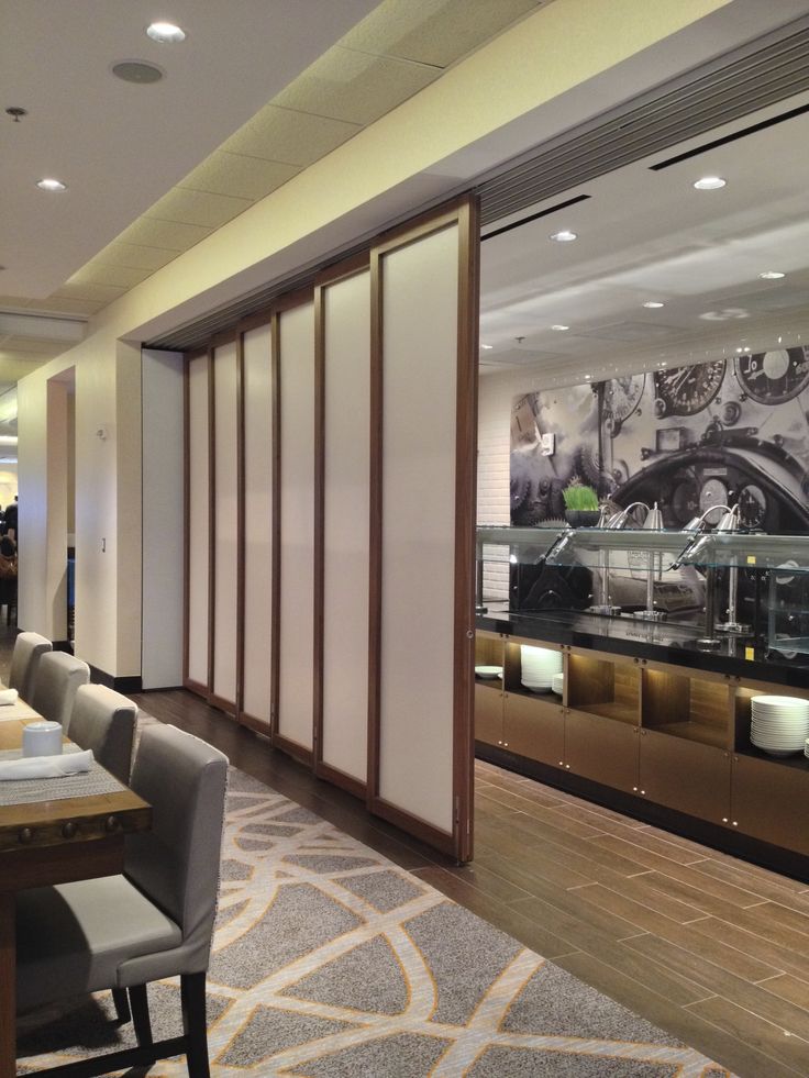 a dining room with tables and chairs in front of a glass display case filled with cars