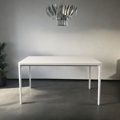 a white table and chair in an empty room with a chandelier hanging from the ceiling