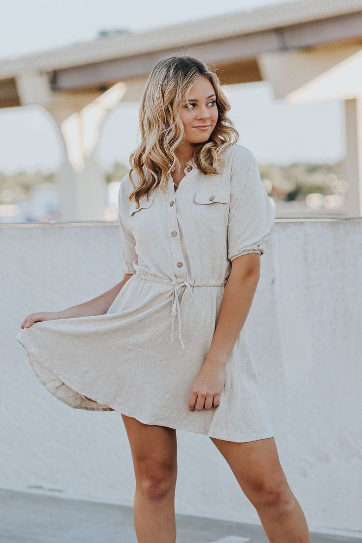 a woman in a white dress posing for the camera with her hand on her hip