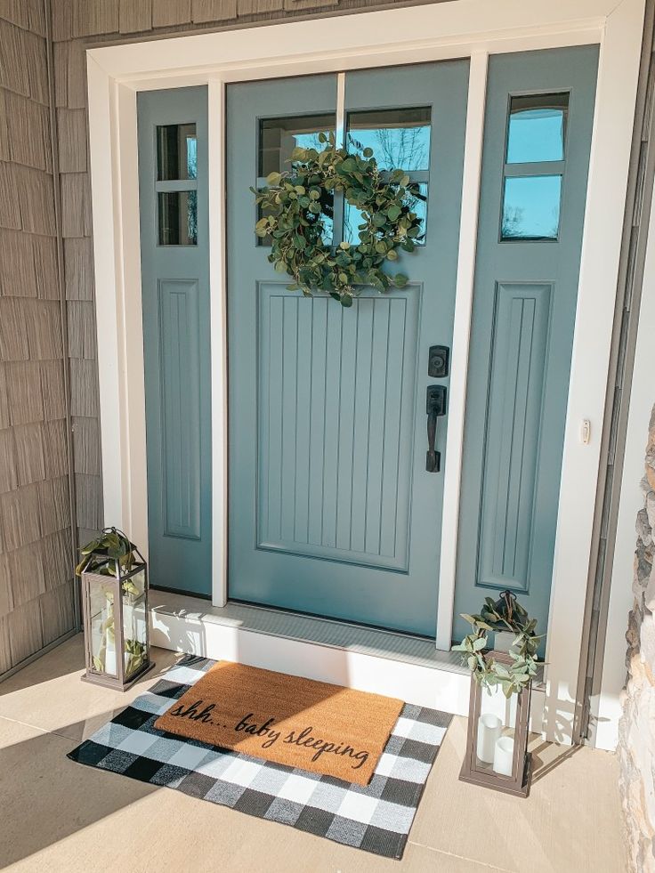 a blue front door with a welcome mat and two lanterns