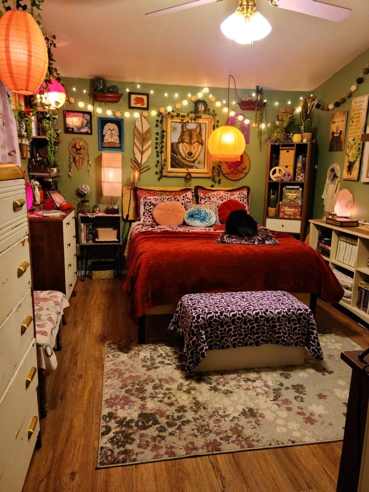 a bedroom decorated in green and red with pictures on the wall above the bed, lights hanging from overhead