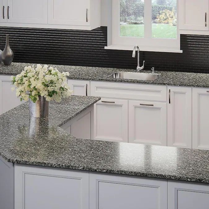 a kitchen with granite counter tops and white cabinets in the center, along with a vase filled with flowers