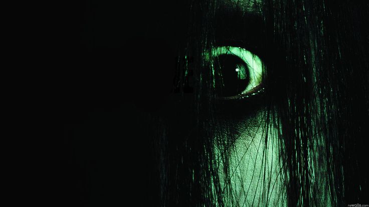 a woman's eye glowing in the dark with long hair and green eyeshade