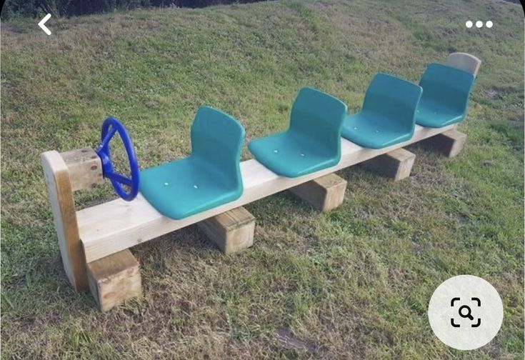 three blue chairs sitting on top of a wooden bench in the middle of a field