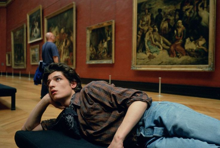 a young man laying on the floor in an art museum