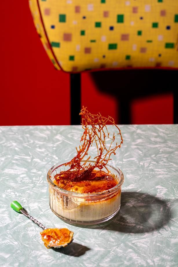 a small glass bowl filled with food sitting on top of a table next to a yellow chair