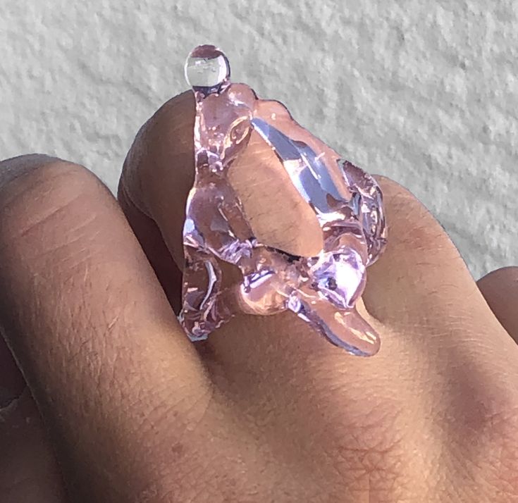 a person's hand with a ring made out of pink glass and silver wire