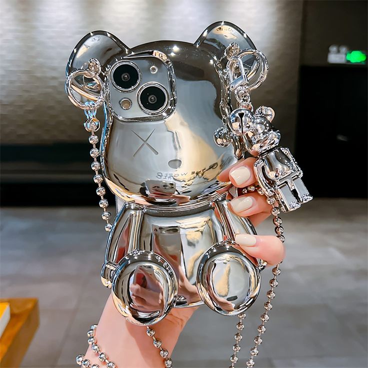 a person holding up a cell phone shaped like a cat with chains around it's neck