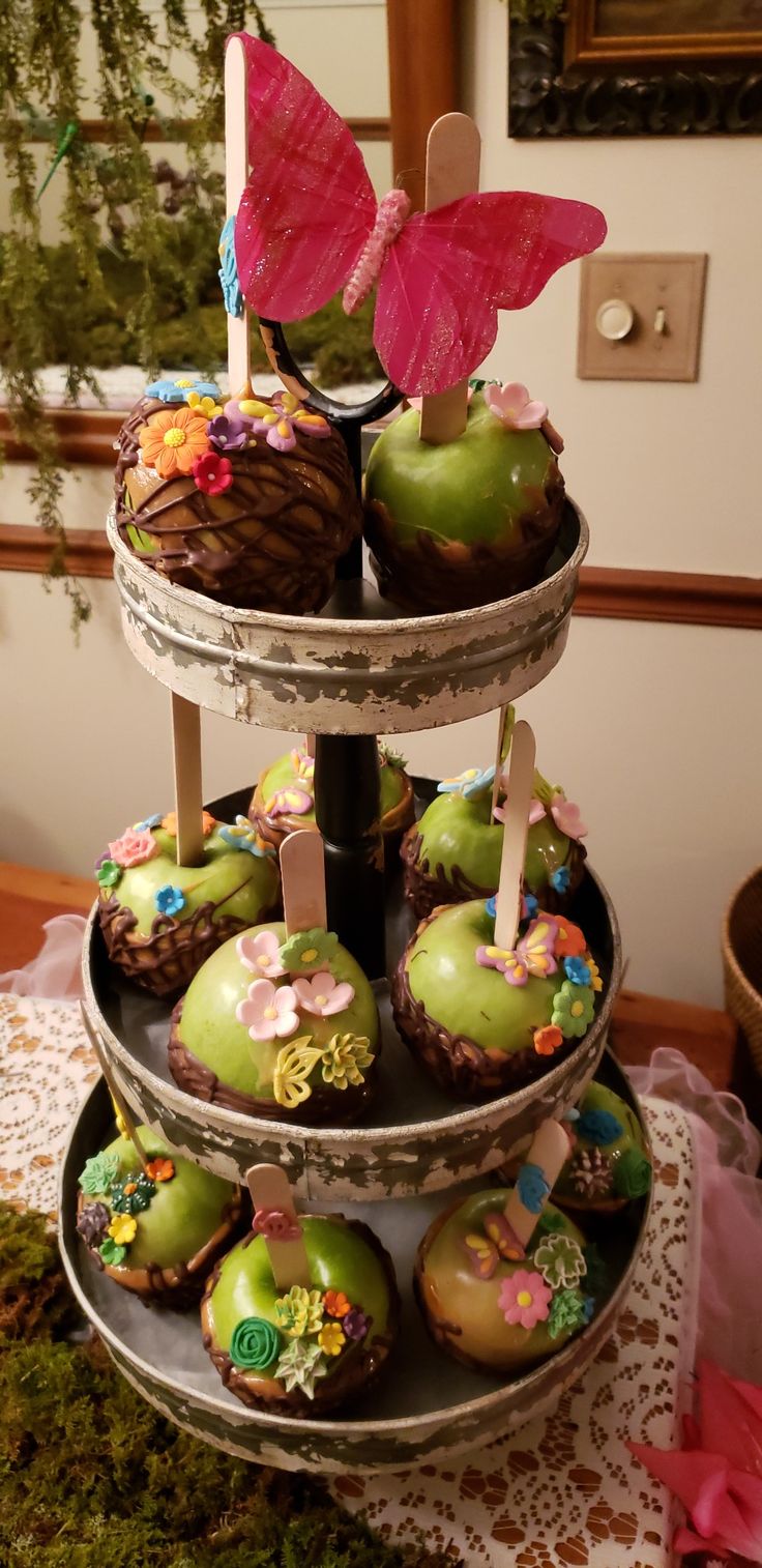 three tiered tray with cupcakes on top of each other and a pink butterfly