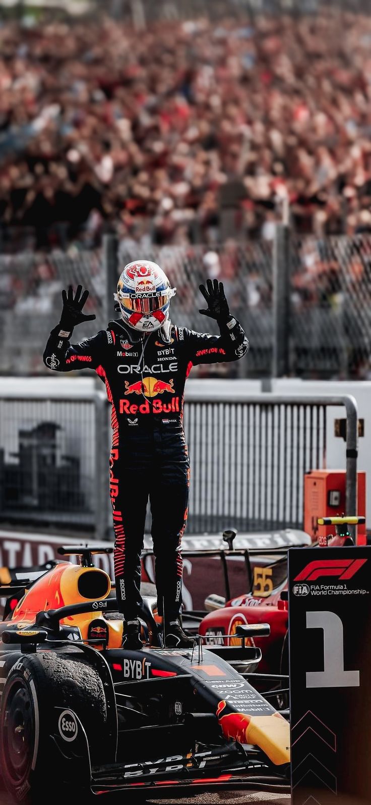 a man standing on top of a race car in front of a crowd