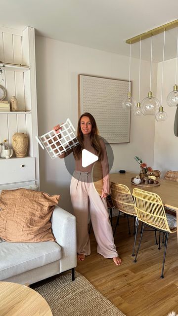 a woman standing in front of a living room filled with furniture and decor on top of a hard wood floor