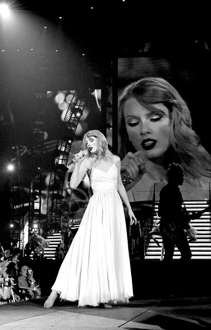 a black and white photo of a woman in a dress on stage with people watching