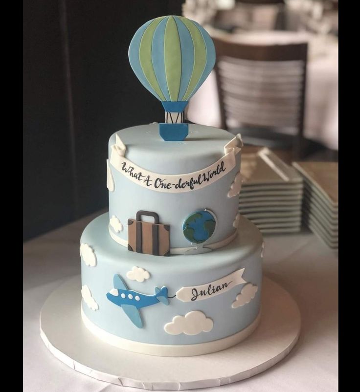 a three tiered cake with a hot air balloon on top and the words travel is one world above it