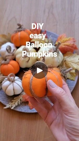 a person holding a small pumpkin on top of a plate