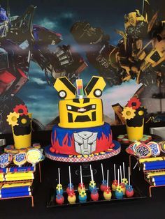 a table topped with cake and cupcakes covered in fondant robots on top of it