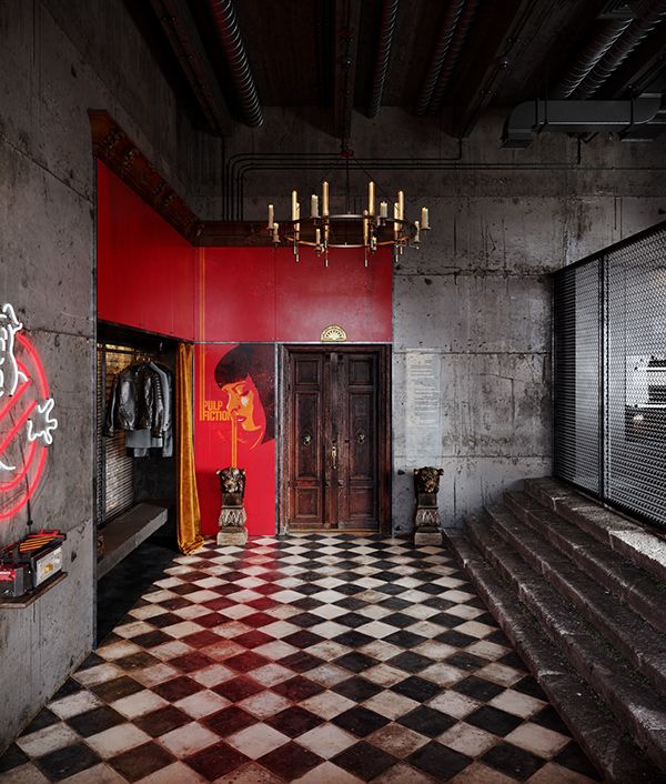 a room with red walls and black and white checkered flooring, chandelier above the door