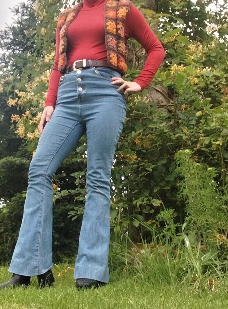 a woman standing in the grass with her hands on her hips and wearing bell bottoms