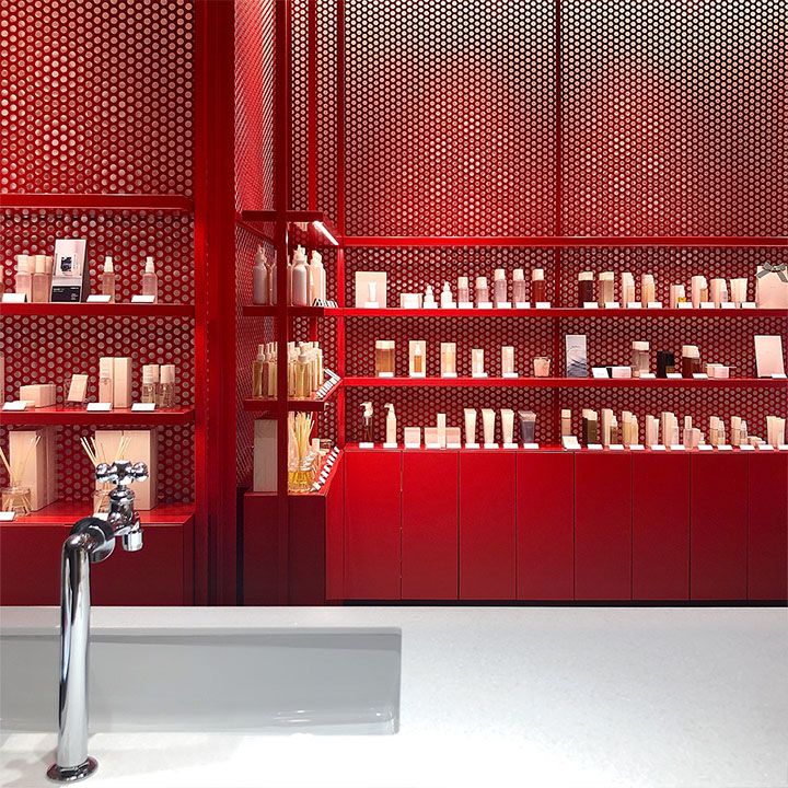 a bathroom sink sitting under a faucet next to a red shelf filled with bottles