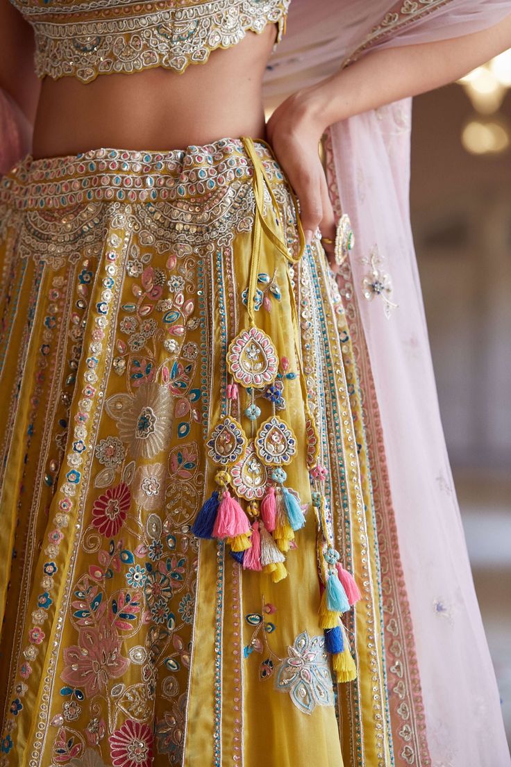 Editor's Note Hand Embroidered Panelled Lehenga Set With Zardosi Details And French Knots Fabric: Organza Color: Yellow Care: Dry Clean Only About the Designer A melange of rich embroideries, appliques, impeccable weaving, brilliant printing, and dyeing, Osaa by Adarsh is a story of India’s rich textile traditions replicated to form wedding couture. Adarsh Makharia saw the endless opportunities to engage the diverse artisans and designs and, with Osaa, weaved together a celebration of India’s he Osaa By Adarsh, Trending Lehenga Designs, Panelled Lehenga, Gold Organza, Blouse Yoke, Wedding Couture, New Kurti, Organza Lehenga, Endless Opportunities