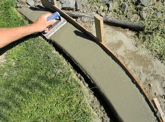 a man laying concrete on the ground