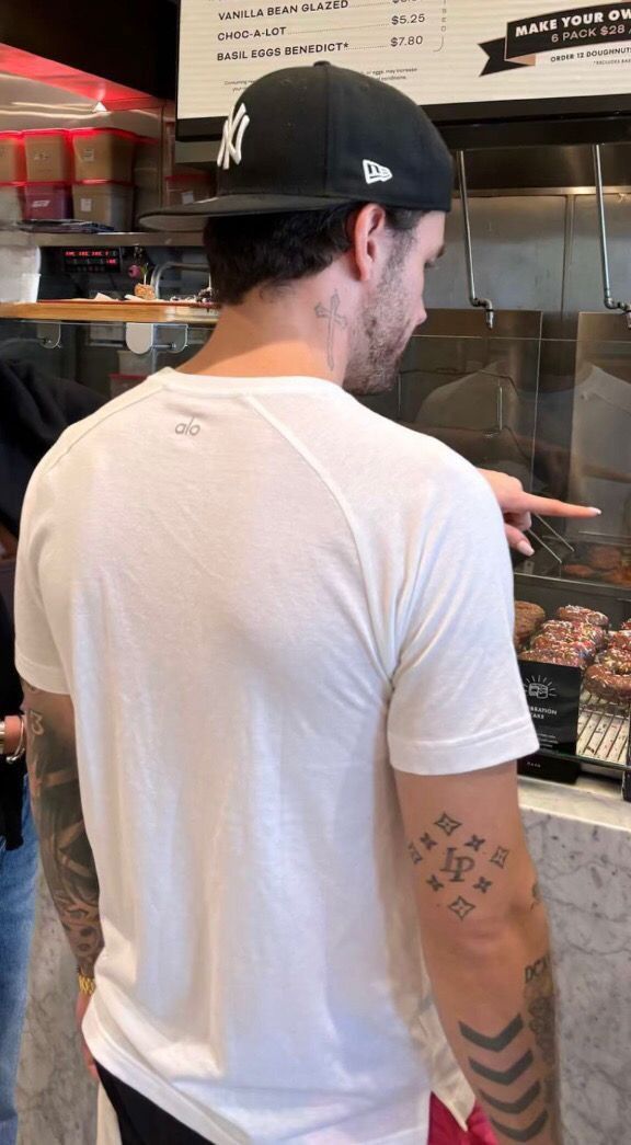 a man with tattoos pointing at food in a display case