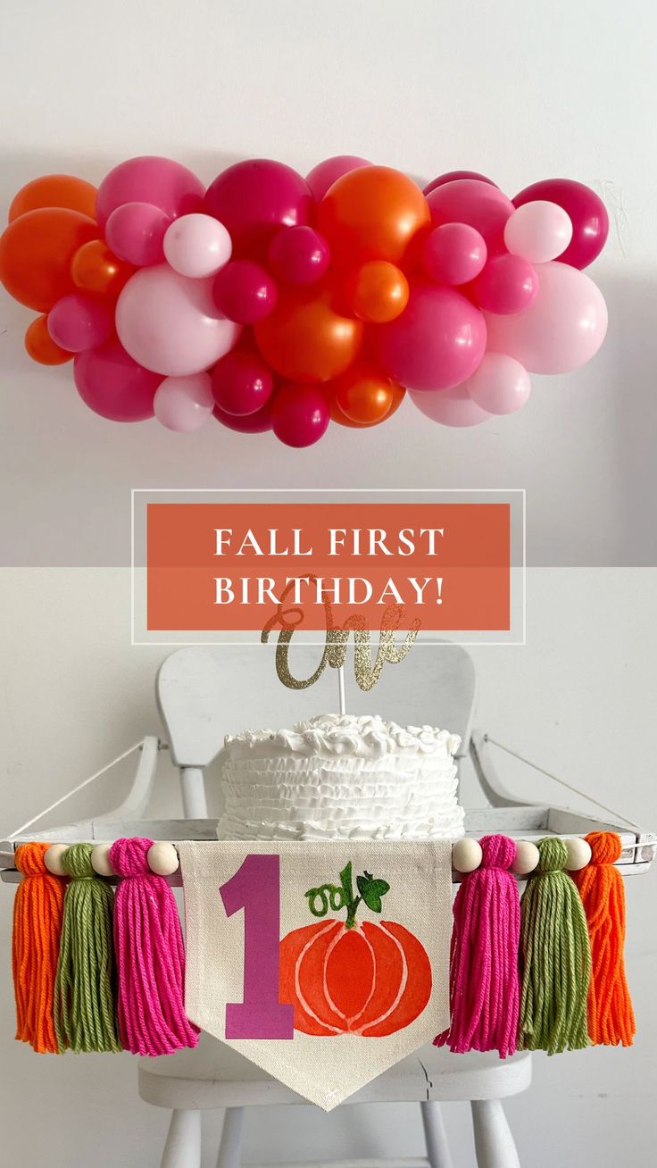 a birthday cake with balloons hanging from the ceiling and a banner that says, fall first birthday