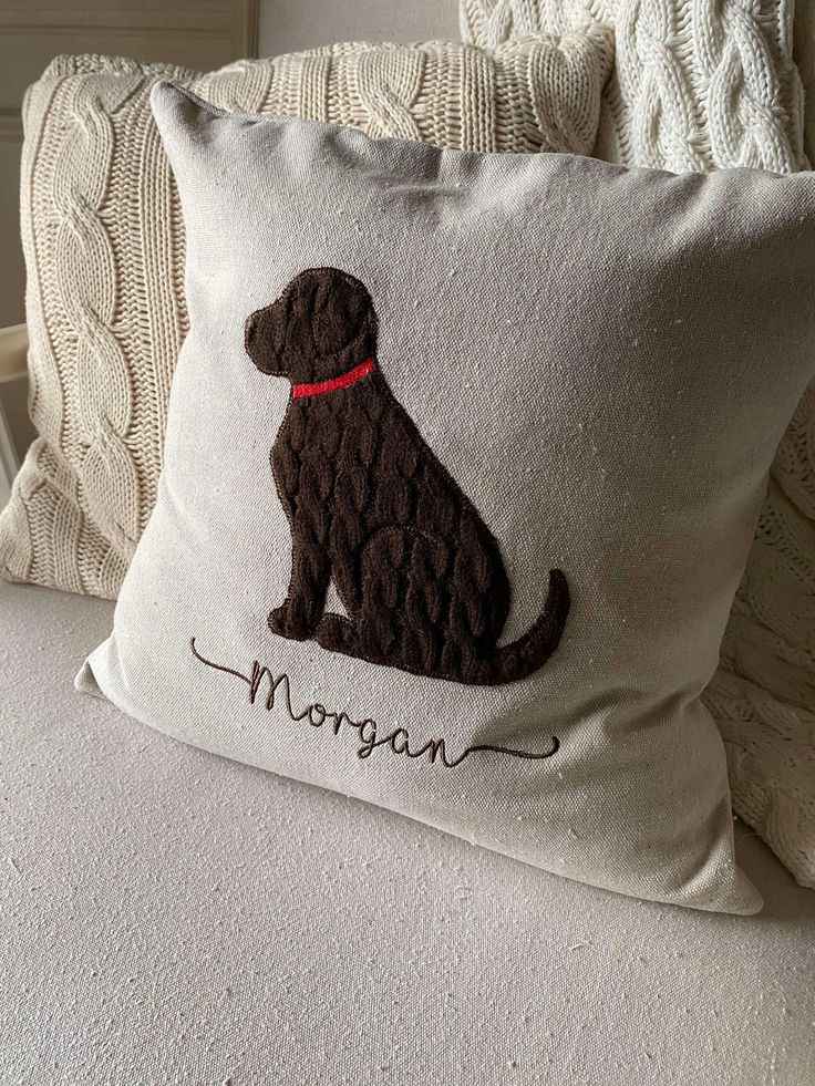 a pillow with a dog on it sitting on a bed next to pillows and blankets