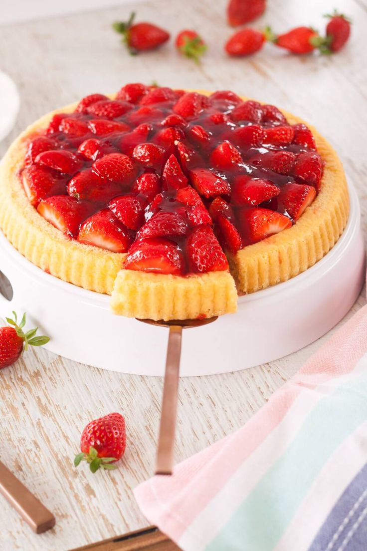 a strawberry pie on a white plate with strawberries around it