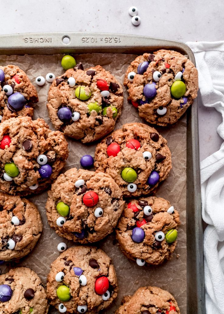 chocolate chip cookies decorated with candy eyes and m & m's on a baking sheet