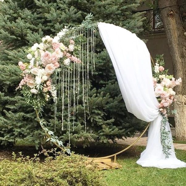 a wedding arch with flowers and greenery hanging from it's sides in front of a tree