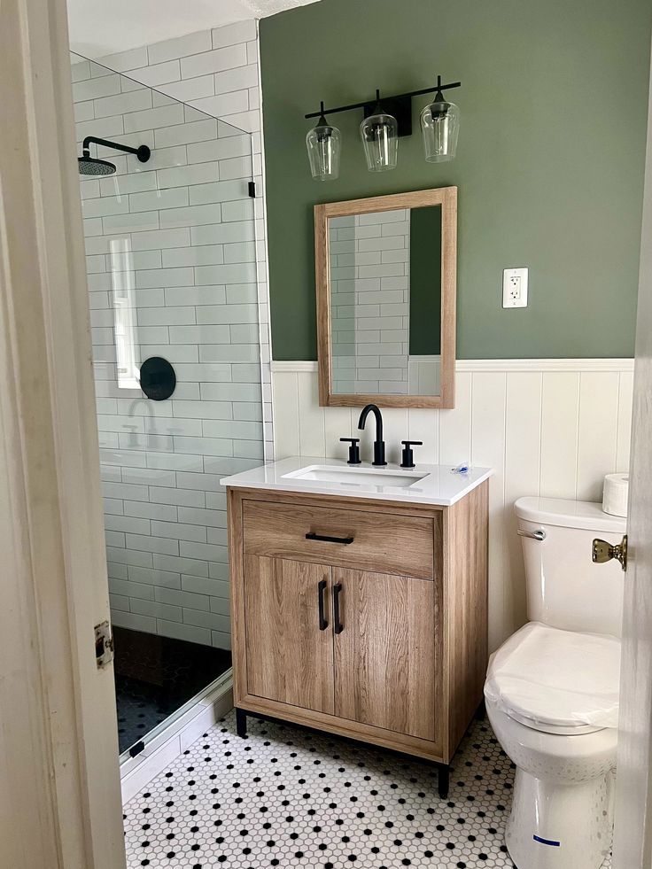 a white toilet sitting next to a wooden sink vanity in a bathroom under a mirror