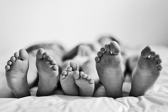 four people are laying down with their feet on the bed