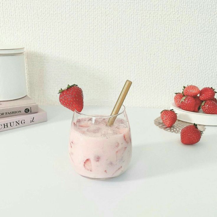 strawberries are sitting on top of a table next to a glass with ice cream and strawberries in it