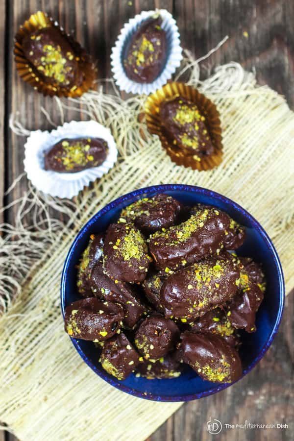 a bowl filled with chocolate covered cookies on top of a wooden table