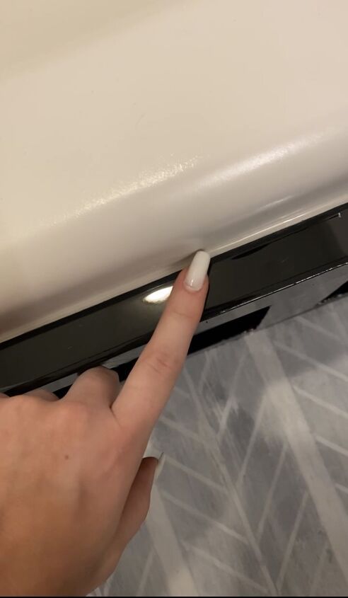 a person is pointing to the side of a toilet seat with their thumb on it