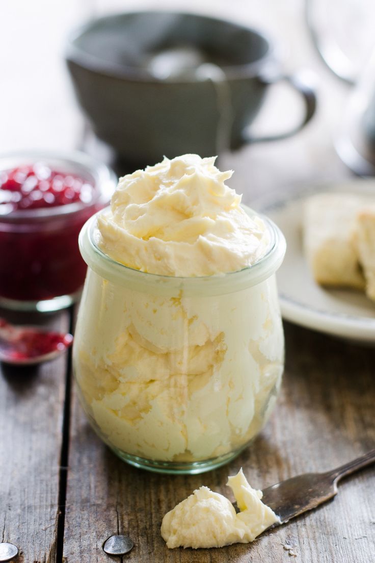 a glass jar filled with whipped cream on top of a wooden table next to a spoon