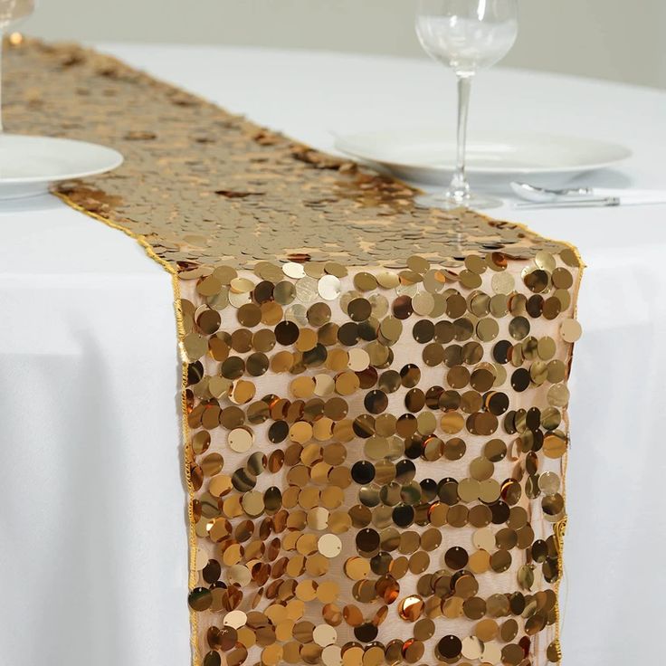 the table runner is decorated with gold sequins and has a wine glass on it