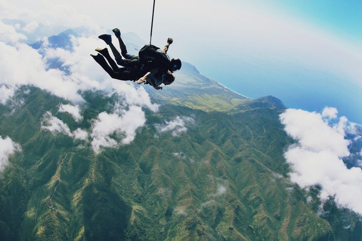 a man is in the air with his feet up above the clouds and mountain tops