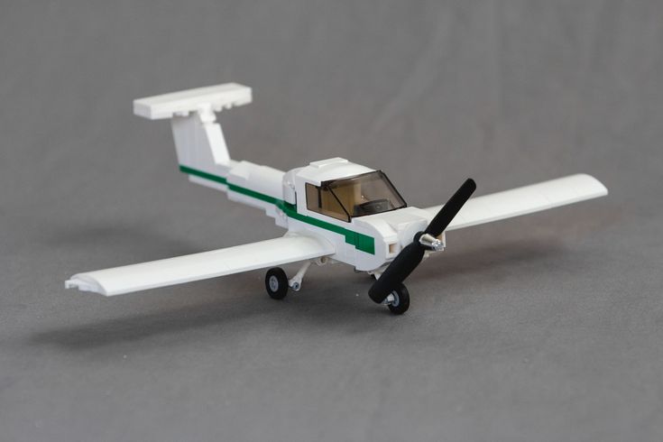 a small white toy airplane on a gray surface with a black nose and green stripe