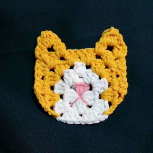 a crocheted animal brooch with a pink nose