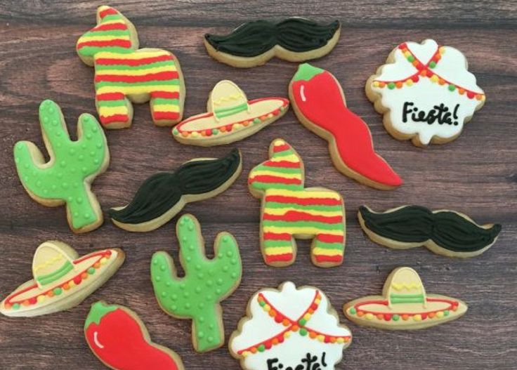 decorated cookies with mustaches, hats, and sombreros are arranged on a wooden surface