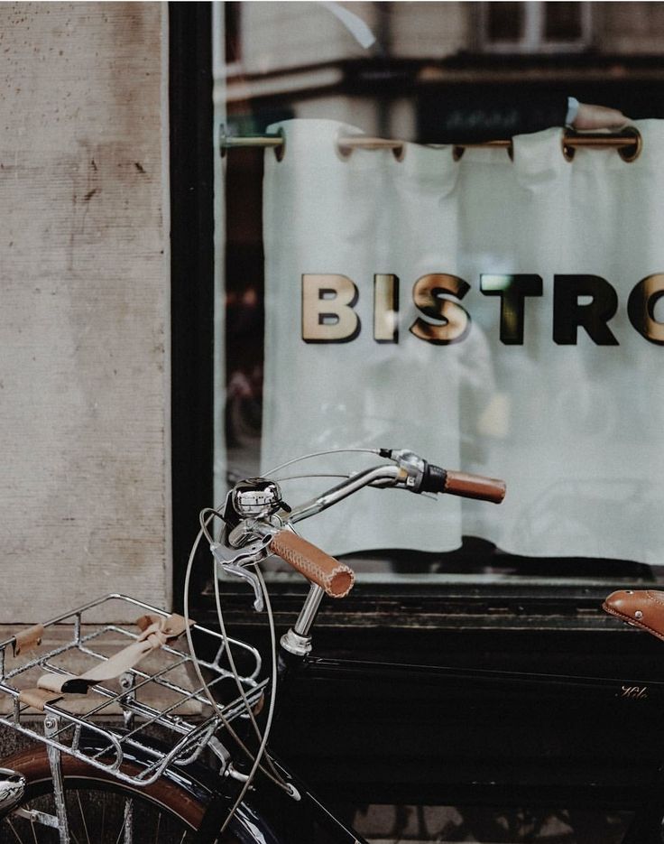 an old bicycle is parked in front of a bistro shop window with the word bistro on it