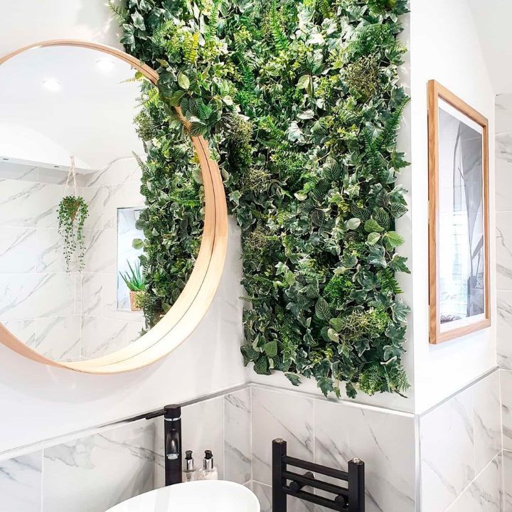 a bathroom with a mirror, sink and plants on the wall in it's corner