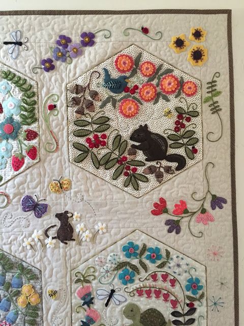 a quilted wall hanging with flowers and cats on it's sides, along with other embroidered designs