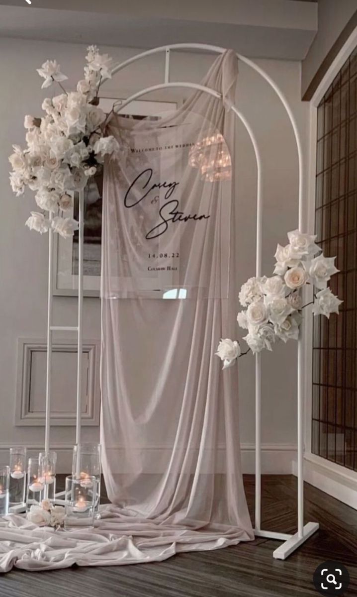 a white wedding arch with flowers and candles