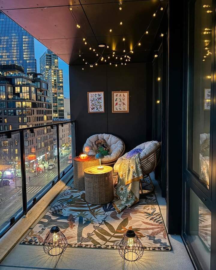 a balcony with two wicker chairs and a table on top of the rug in front of it